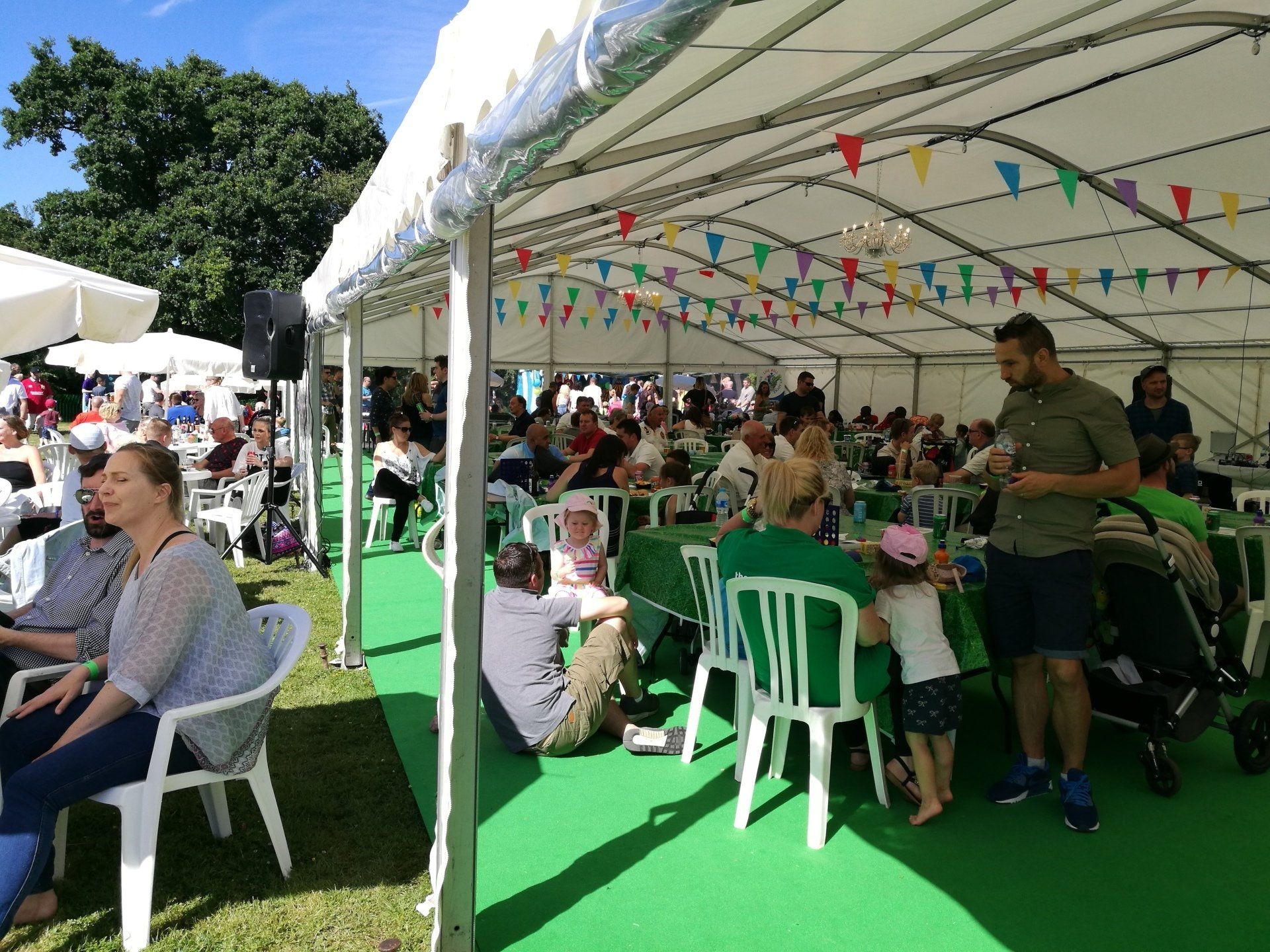 A group of people are sitting under a tent at a festival.