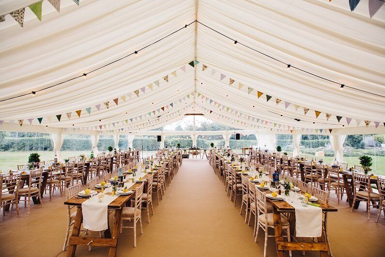 A large marquee with tables and chairs set up for a wedding reception in Worcestershire