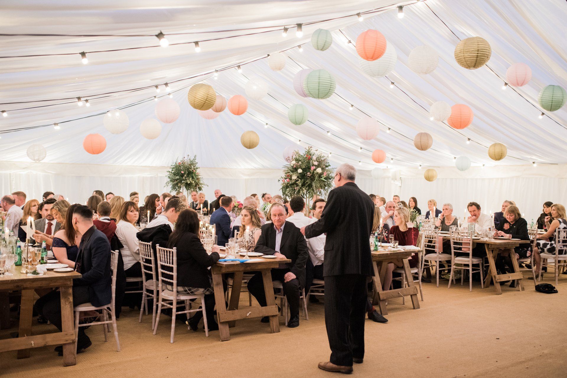 A large group of people are sitting at tables in a tent.