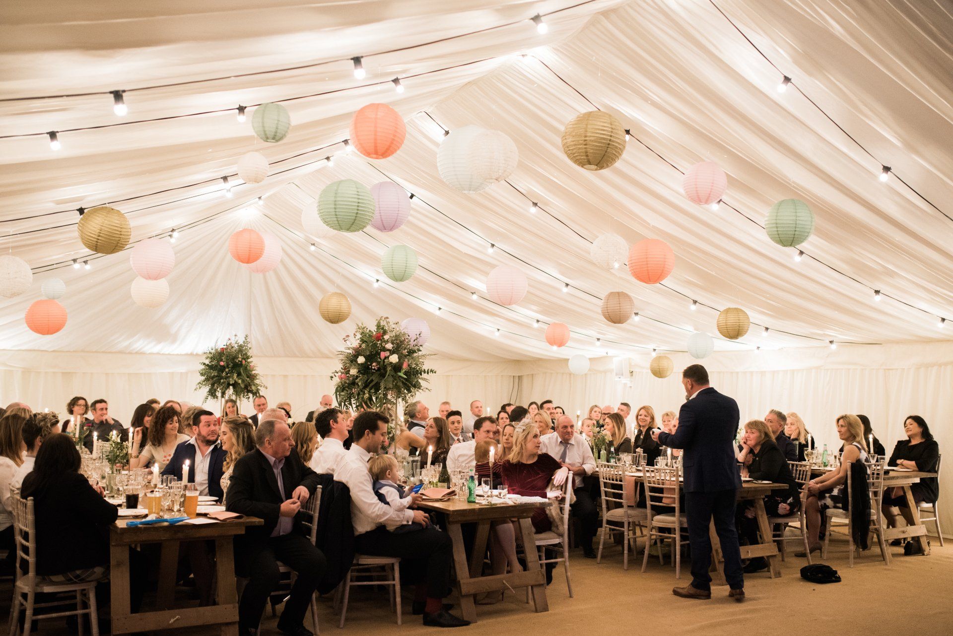 A large group of people are sitting at tables in a tent.