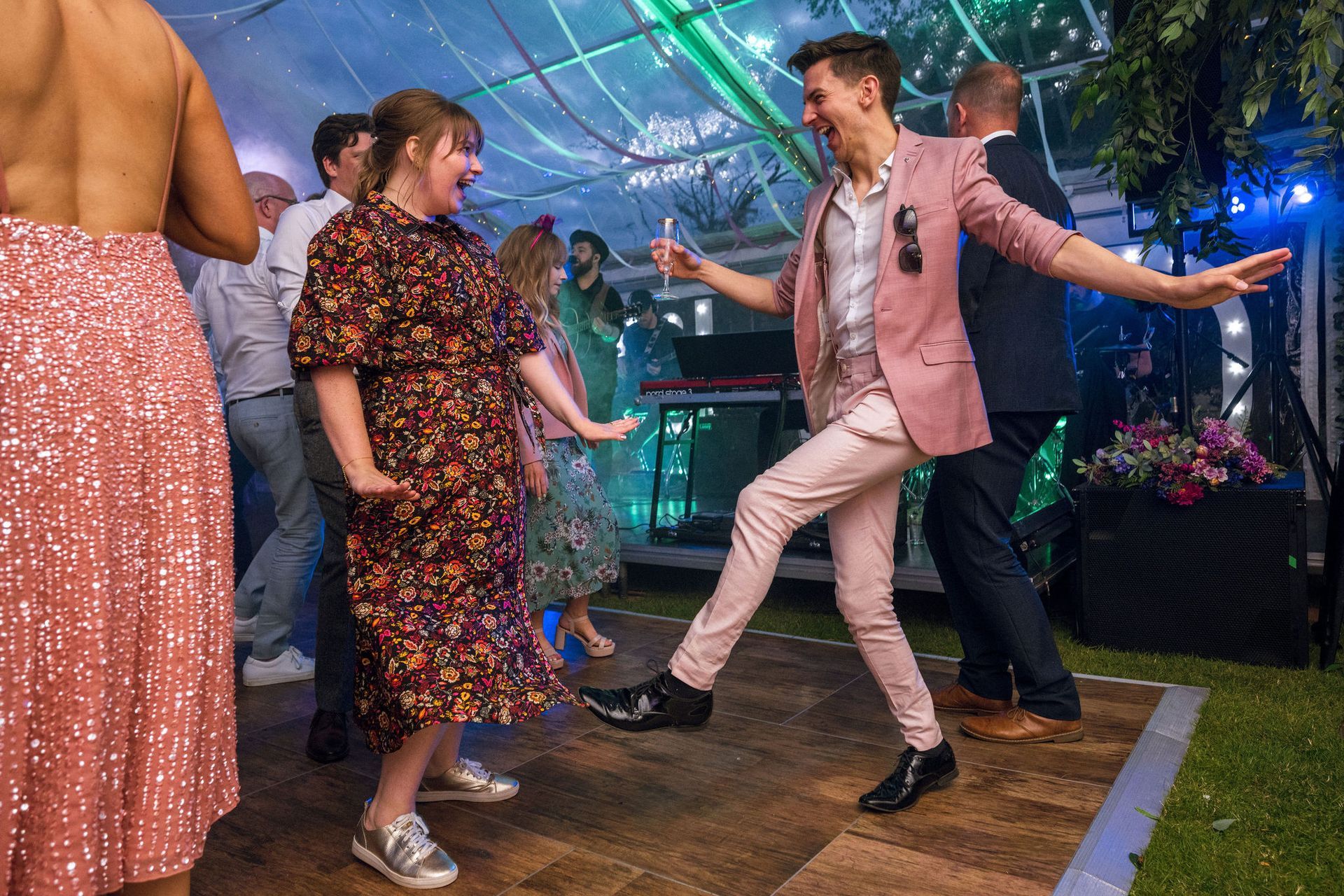 A group of people are dancing on a dance floor at a wedding reception.