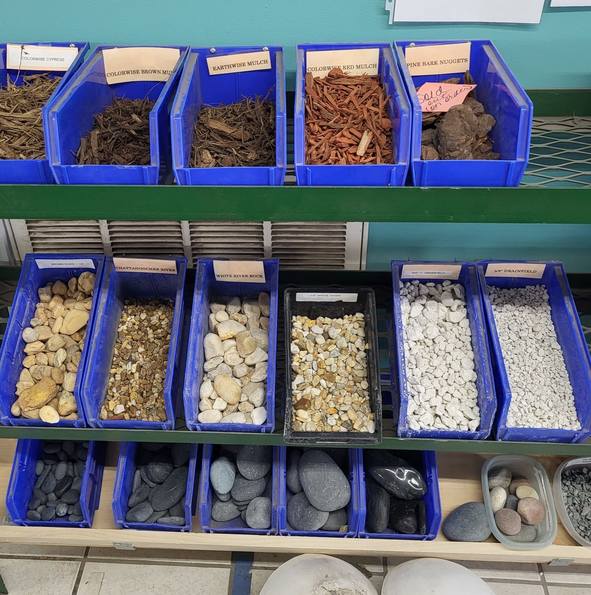 View of a wide selection of landscaping materials like mulch or gravel in blue trays.