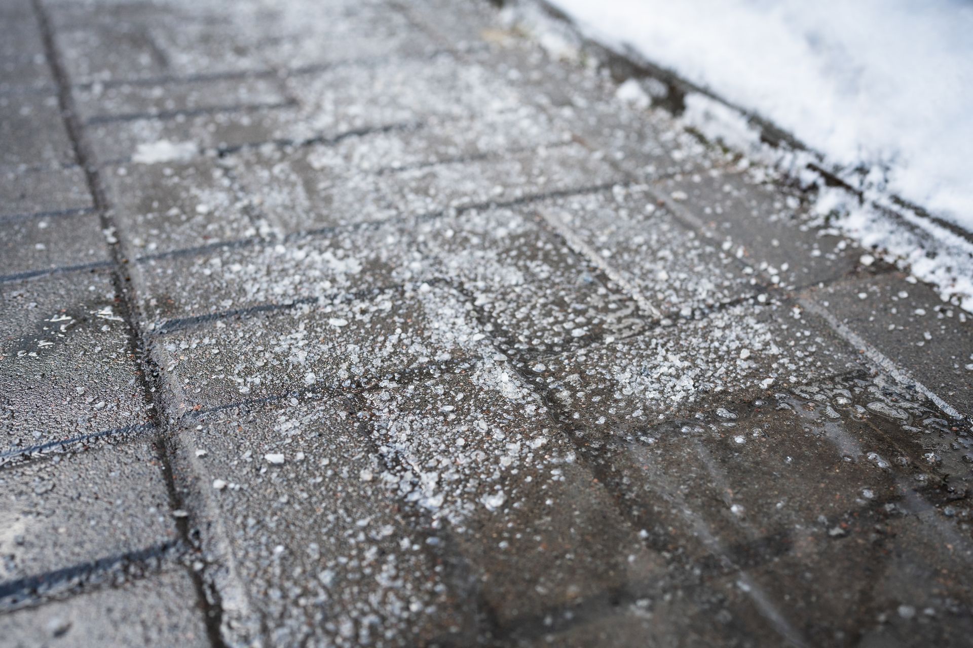 Close-up of road treated with ice melt chemicals and salt during winter for anti-icing.