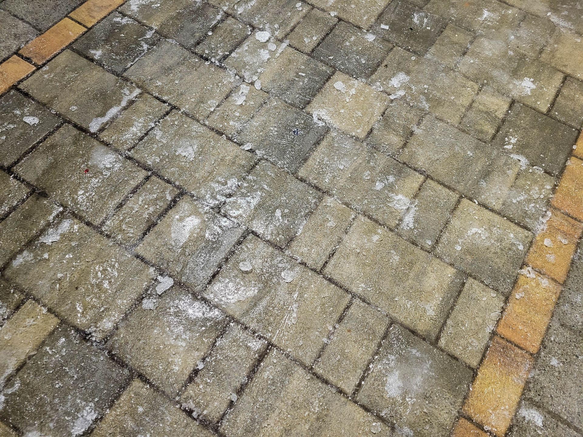 Slippery icy pavement before ice melt application on winter street with frozen paving stone surface.