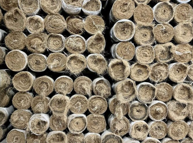 Stacked rolled hay bales filling the frame, showing circular ends in tan and gray tones