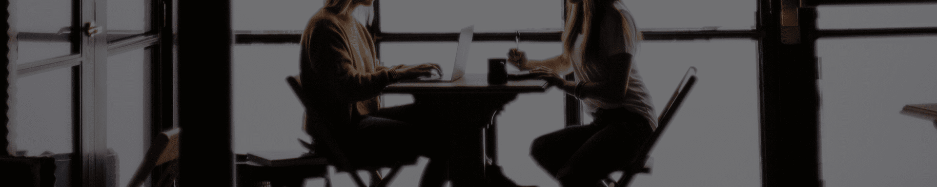 A couple of people are sitting at a table in a dark room.