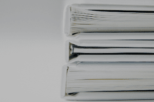 Three binders are stacked on top of each other on a white surface.