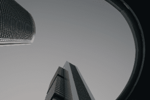 Looking up at a skyscraper through a window in a black and white photo.