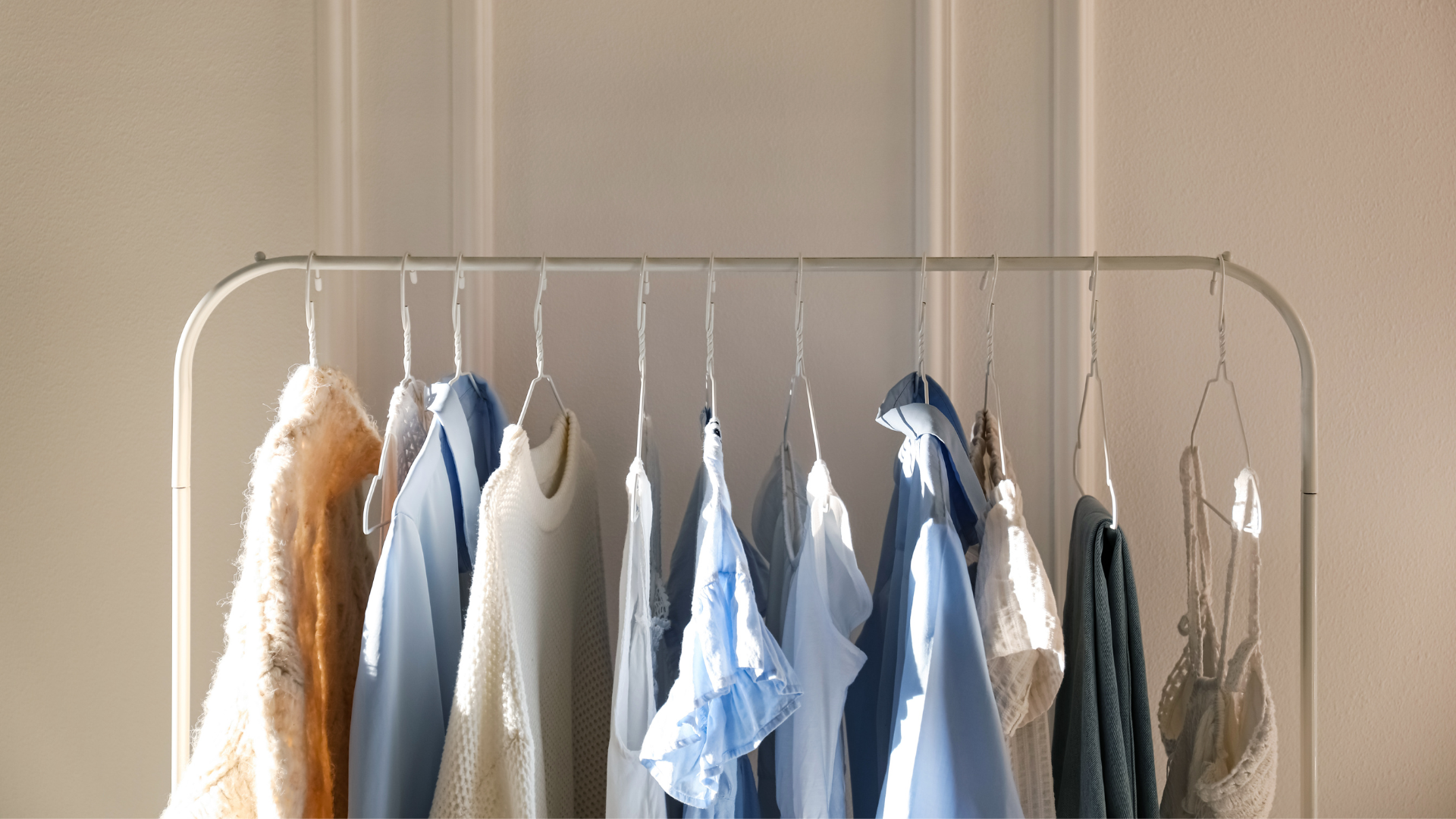 Shirts hanging on a rack in a closet, various muted colors.