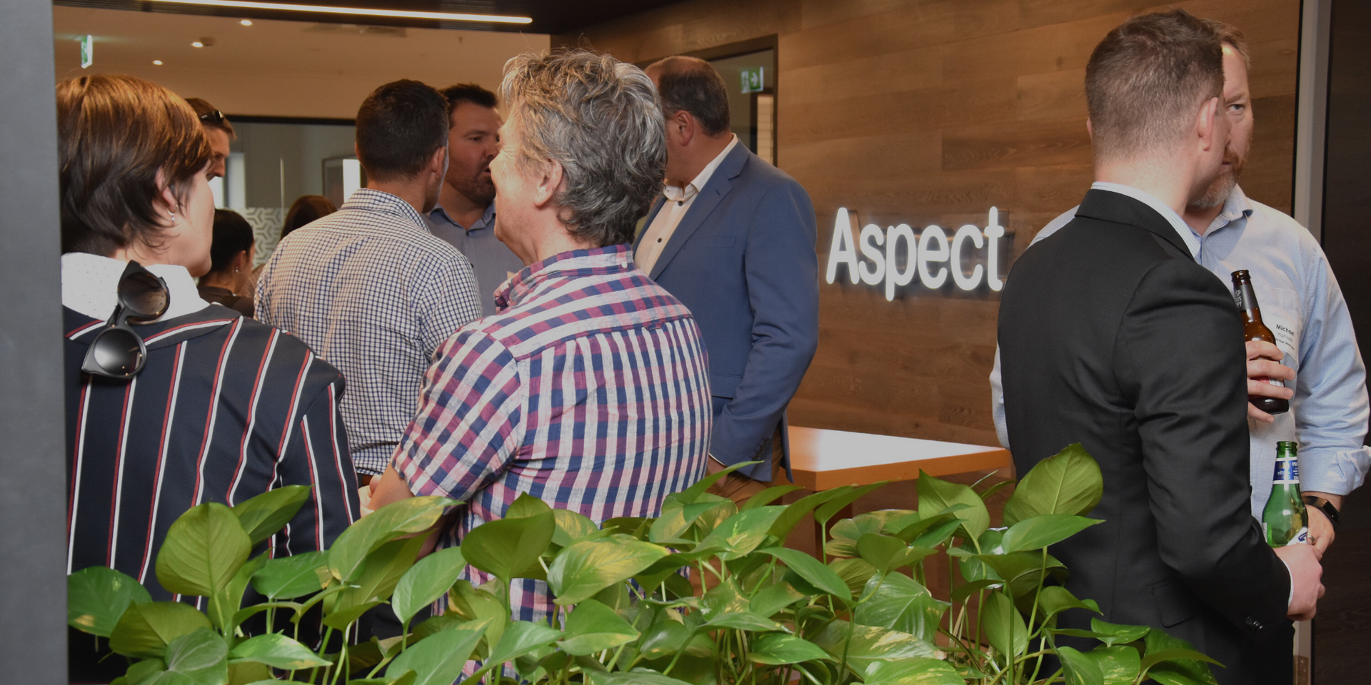 A group of people are standing in front of a sign that says aspect.