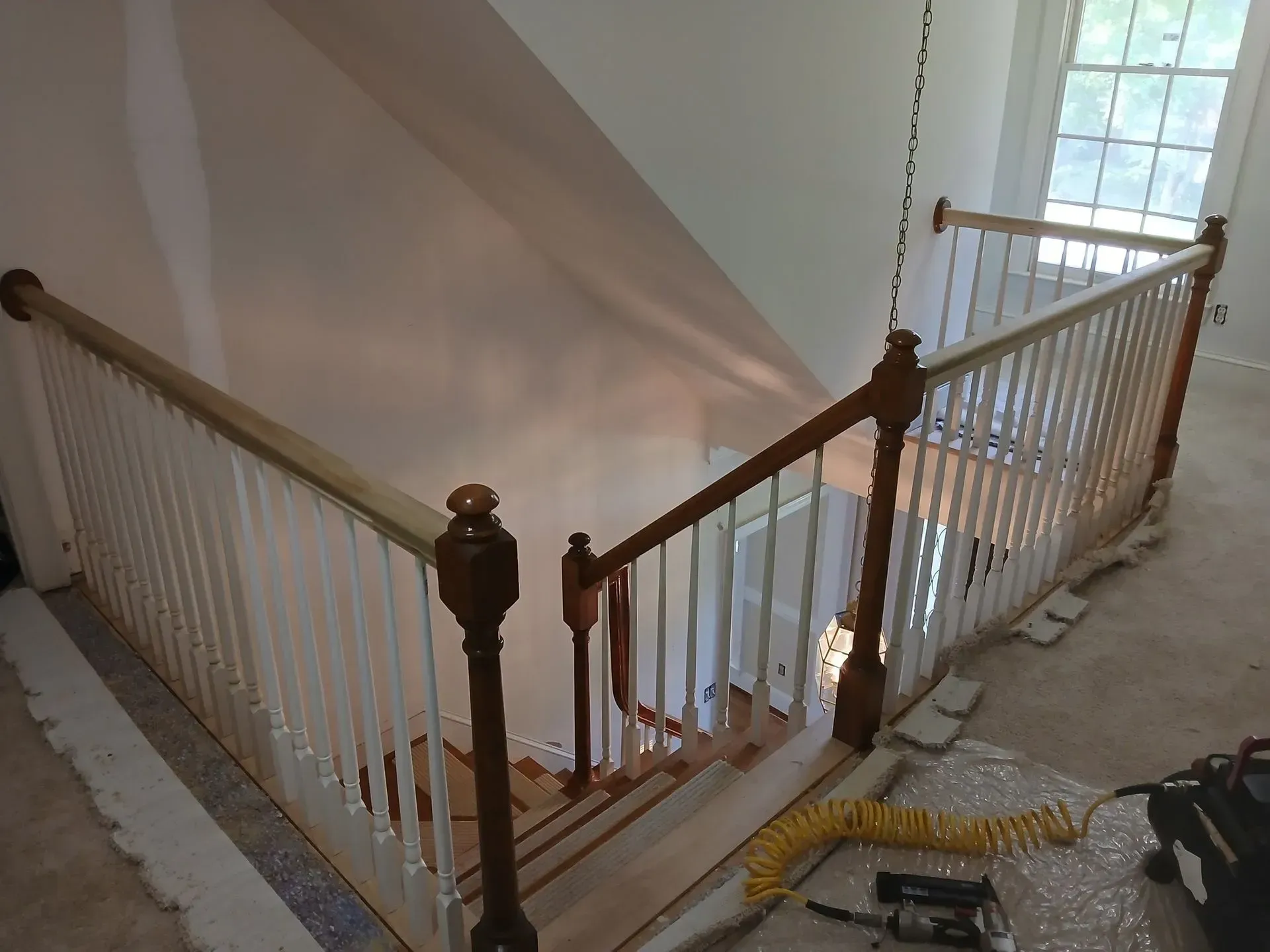 Stairwell with white balusters and dark wood railings beside a bright window