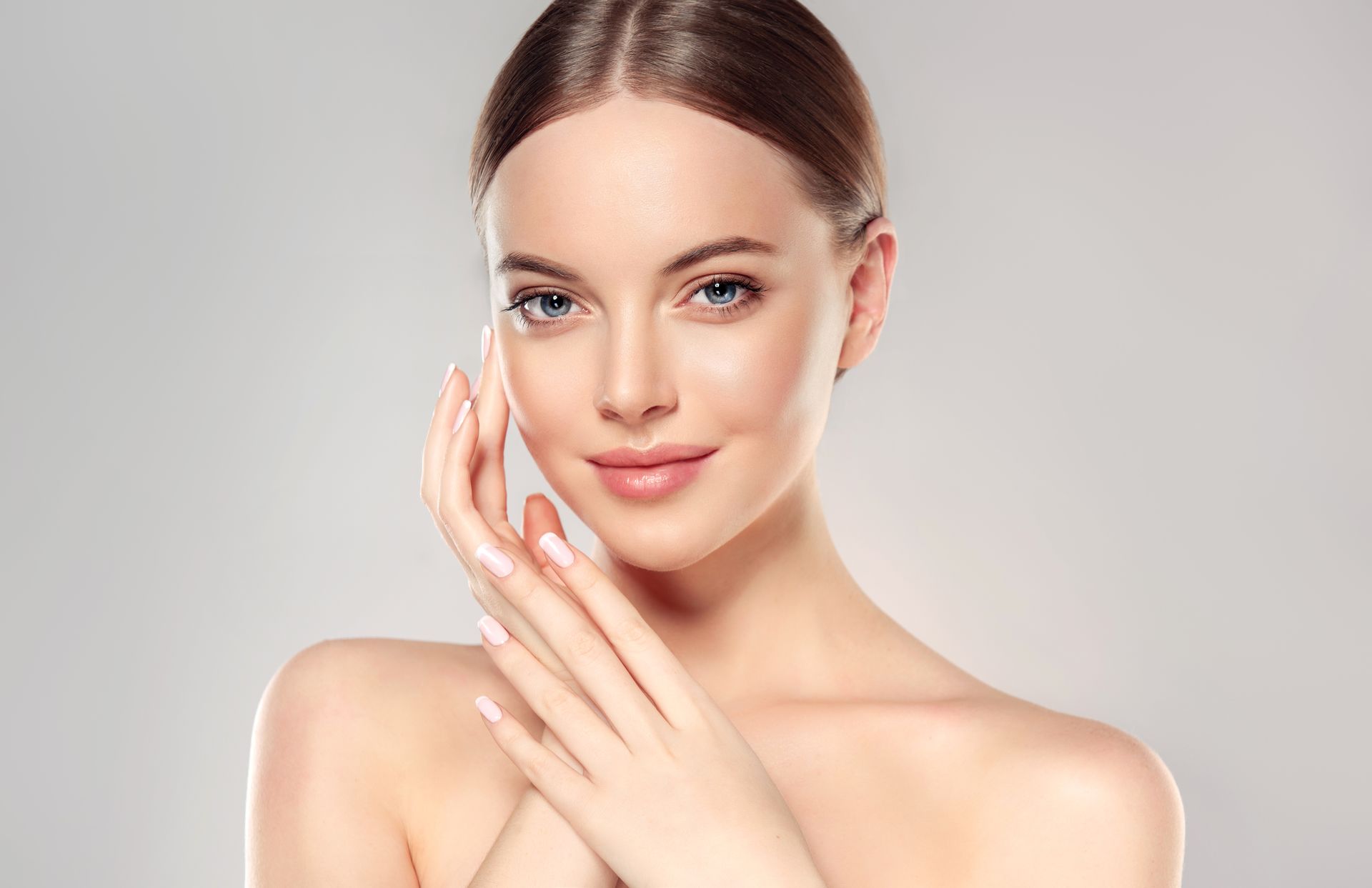 A woman is touching her face with her hands and smiling.