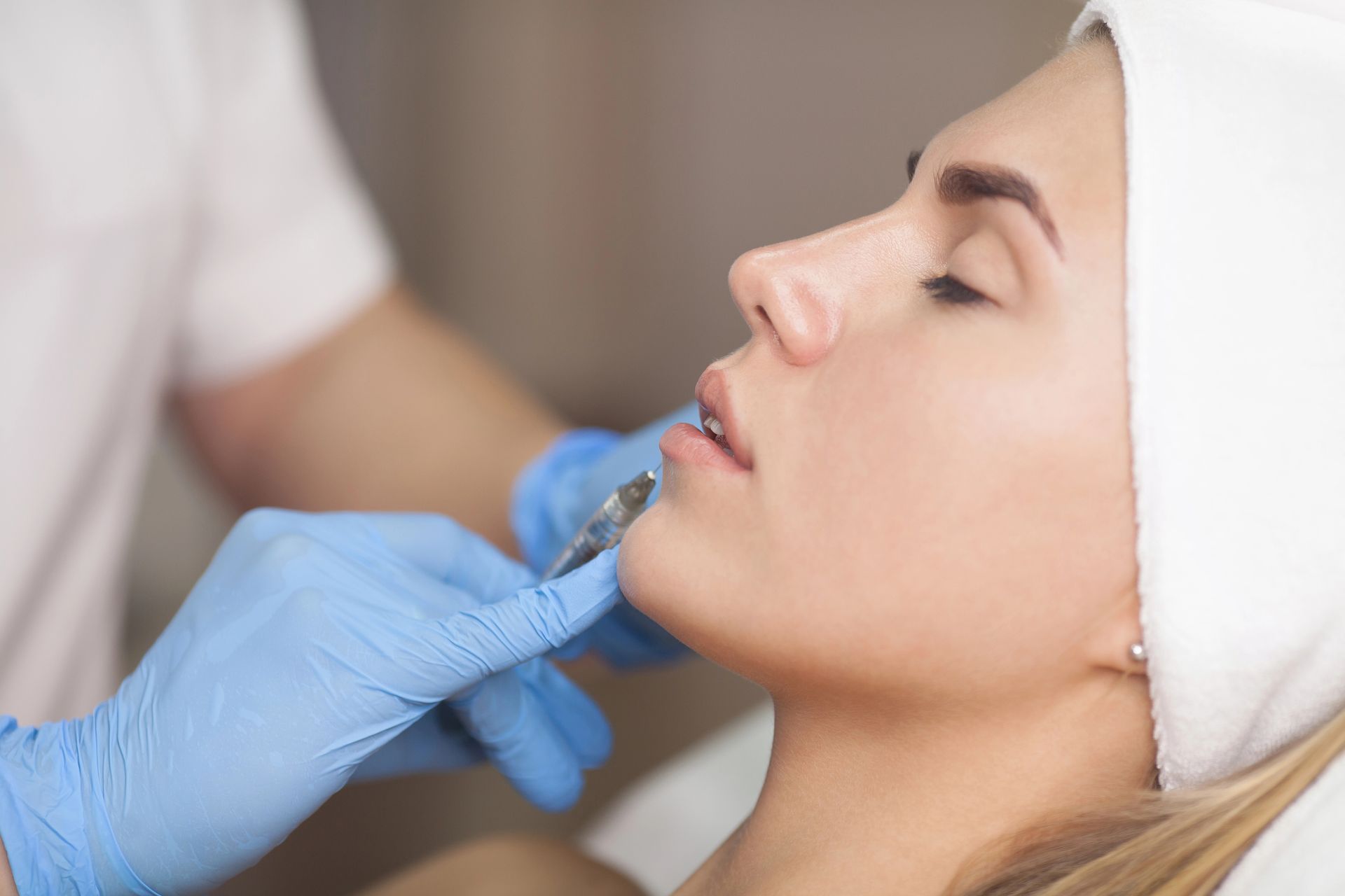 A woman is getting a botox injection in her lips.