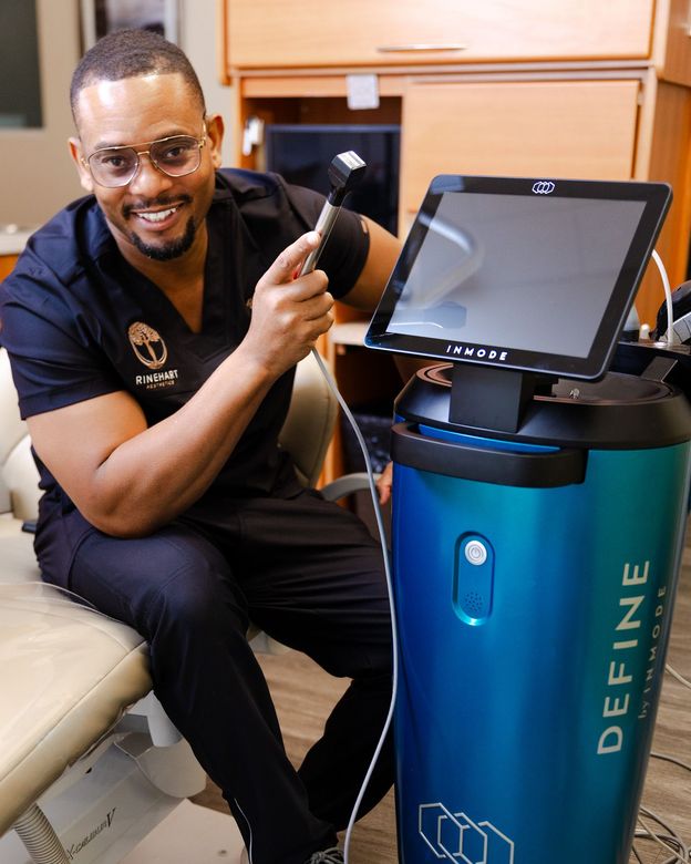 A doctor is sitting next to a machine that says define on it.