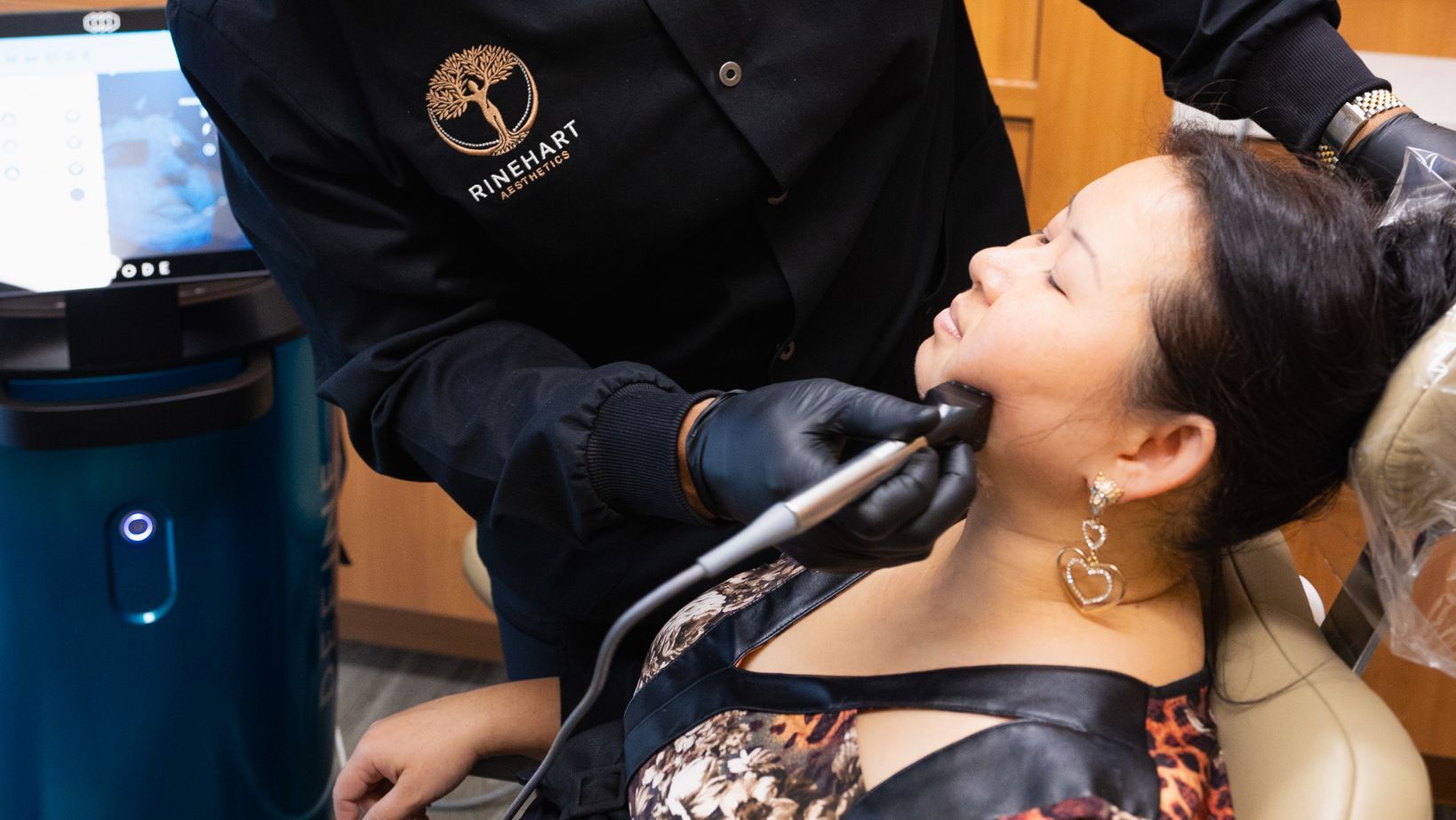 A woman is sitting in a dental chair getting a Forma treatment from a doctor.