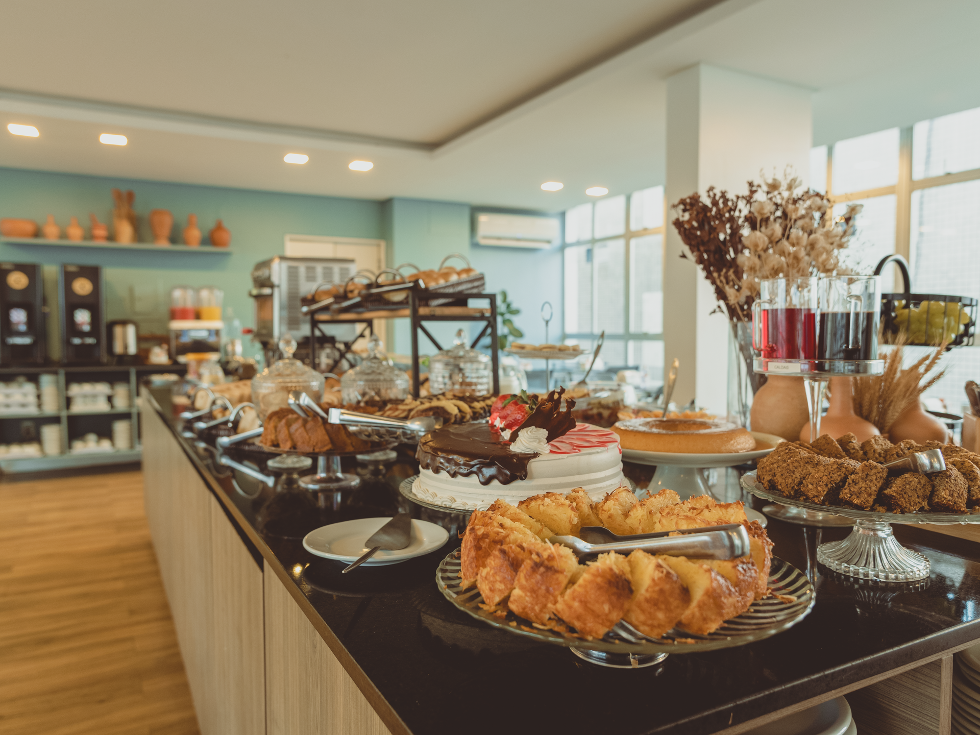 Buffet de café da manhã no restaurante do hotel, com comida exposta e mesas postas para os hóspedes.