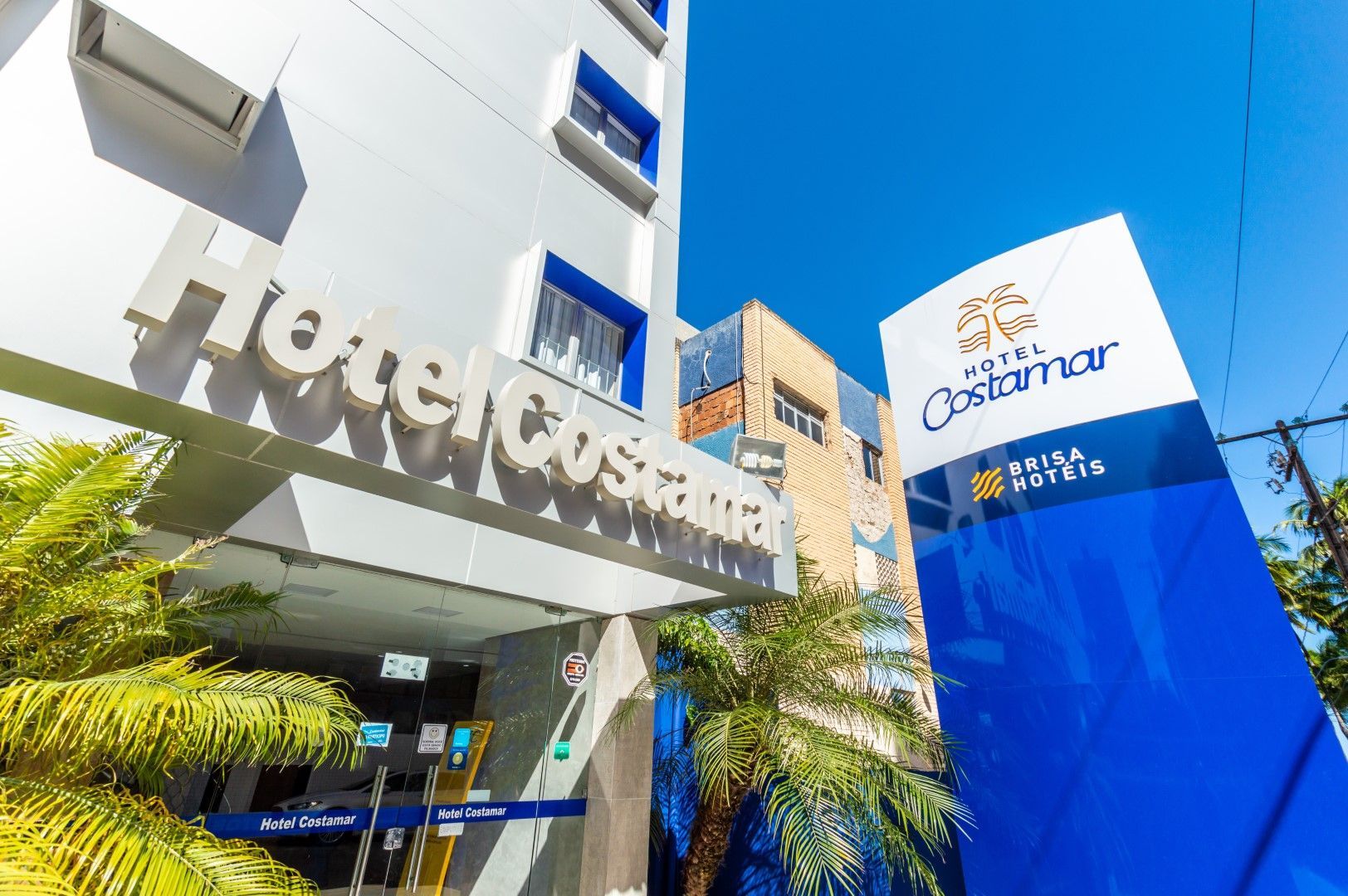 Exterior do Hotel Costamar com fachada e sinalização azul e branca.