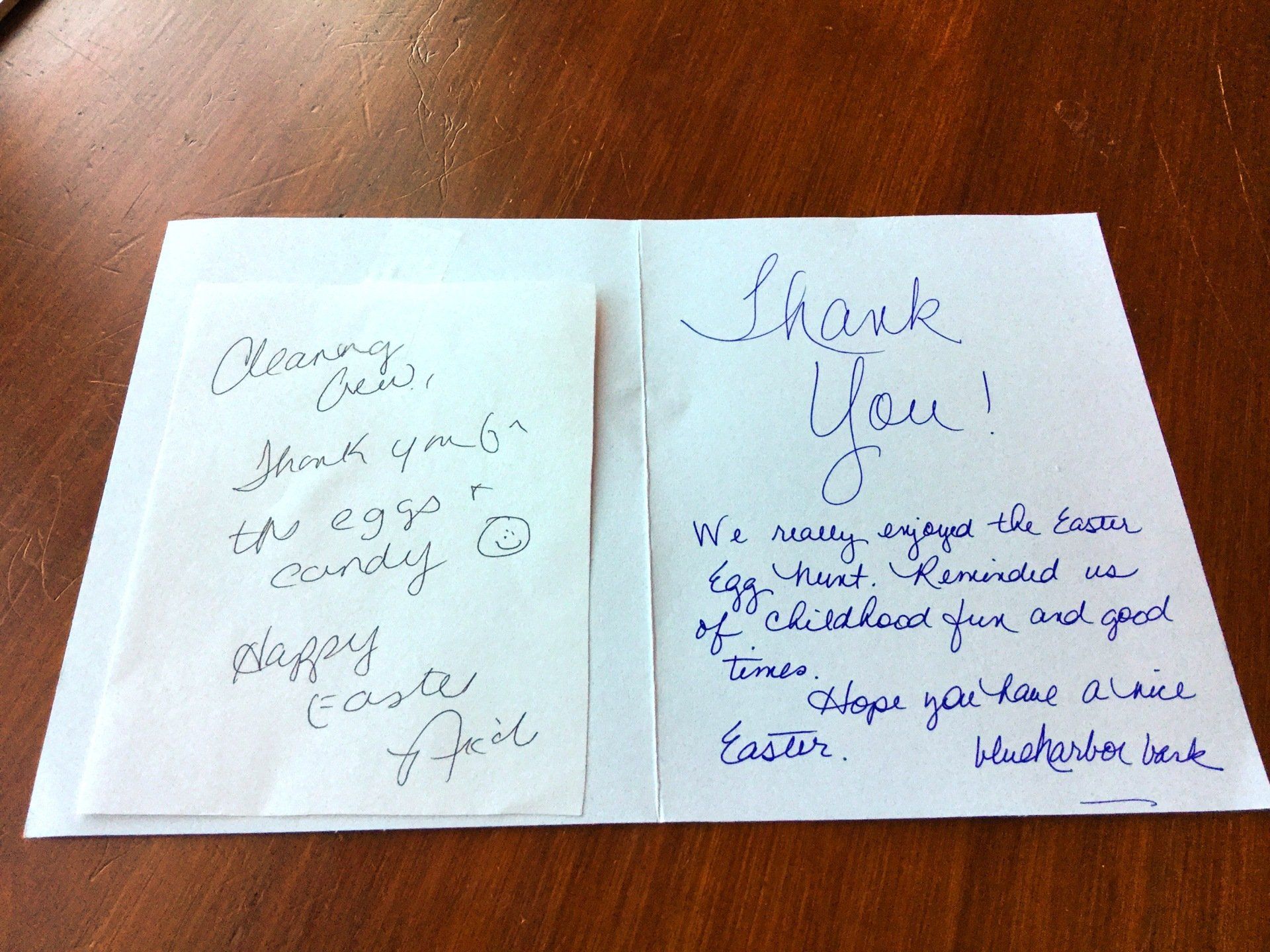 A handwritten thank you note sits on a wooden table