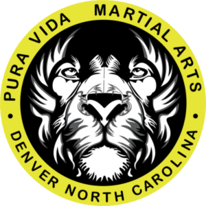 Logo for Pura Vida Martial Arts in Denver, North Carolina, featuring a black and white lion head within a yellow circle.