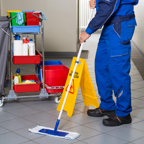 A man is mopping the floor next to a yellow wet floor sign
