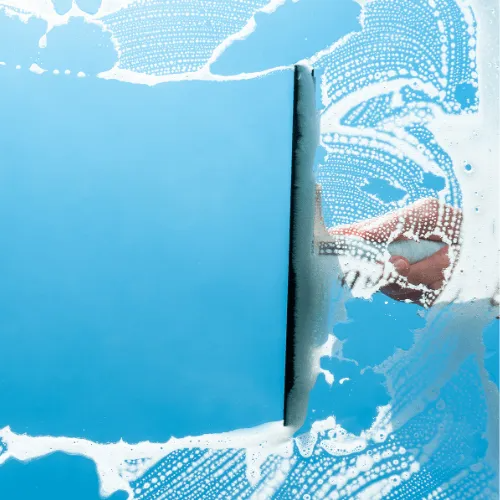 A person is cleaning a window with a sponge.