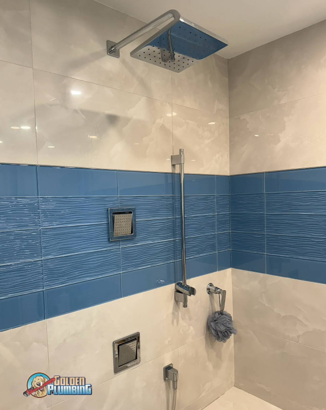 A bathroom with blue and white tiles and a shower head.