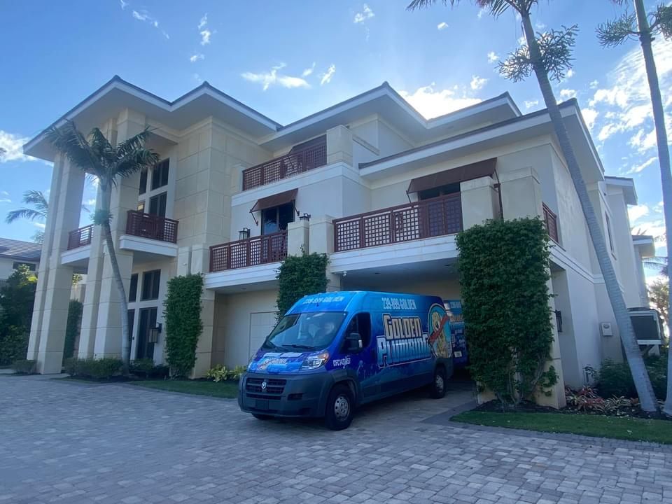 A blue van is parked in front of a large house.