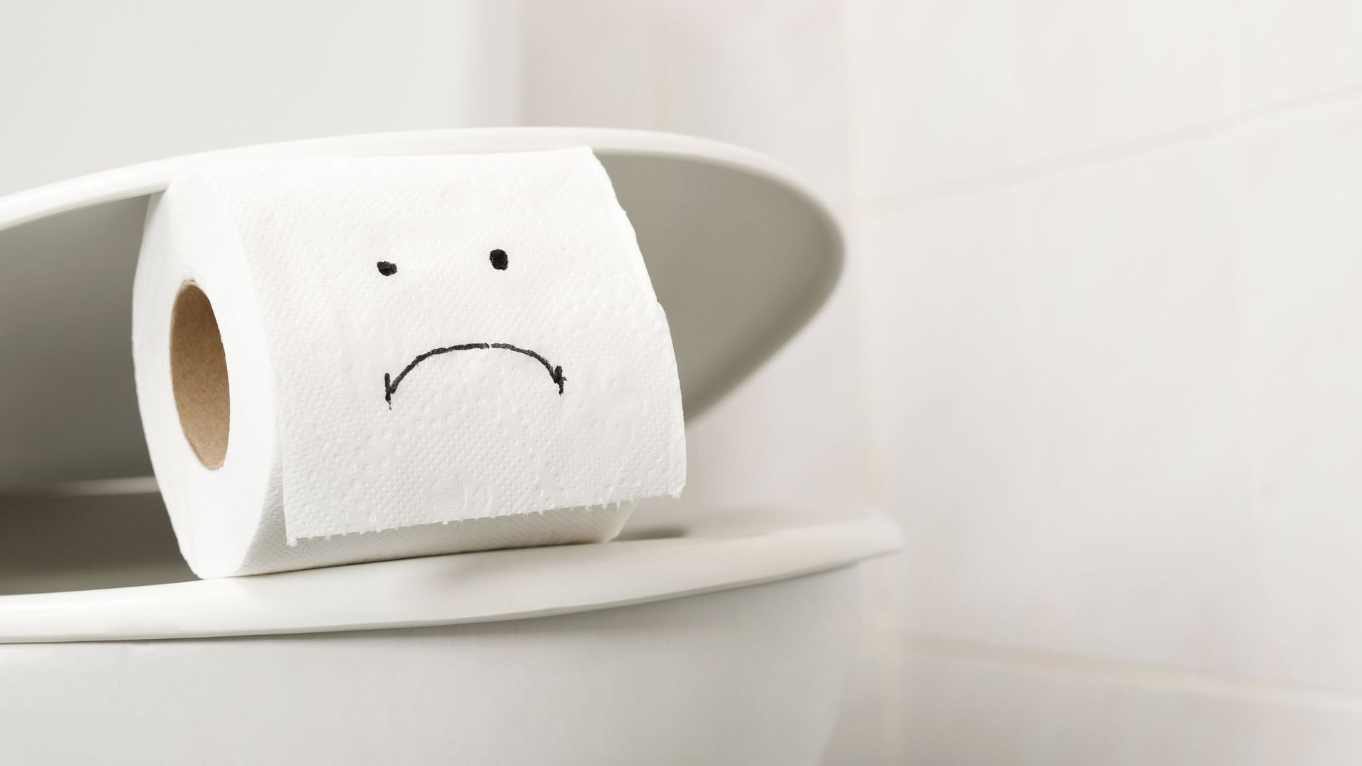 Toilet paper with an unhappy face in a broken toilet that need repairing