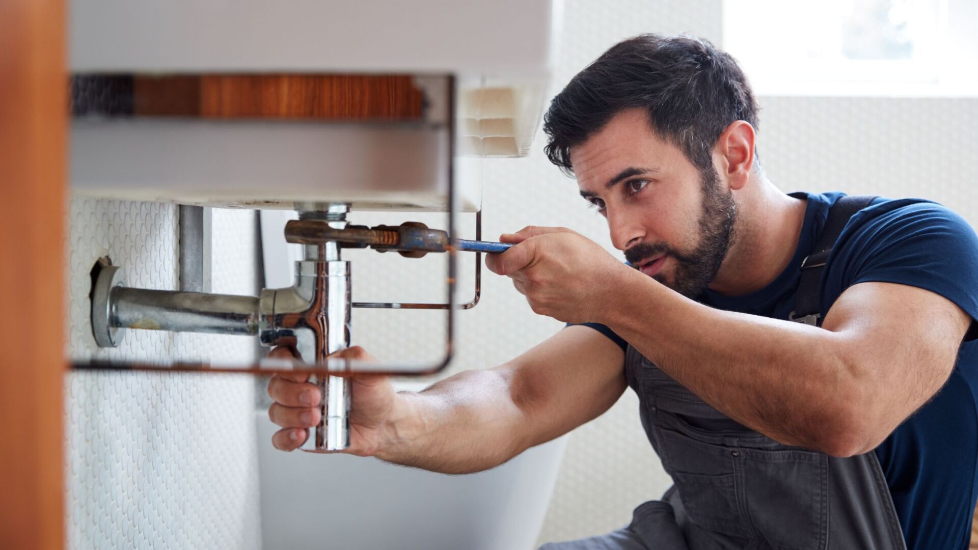 Plumber fixing a kichen sink with a plumbing wrench for an emercency call out