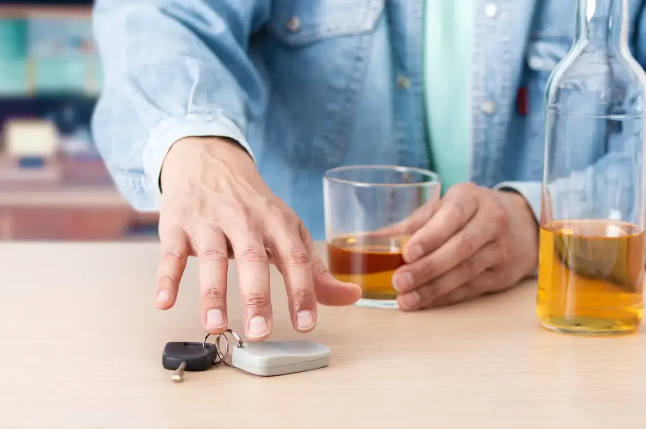 Hand holding car keys and a beer, representing the risk of DUI charges in Ontario