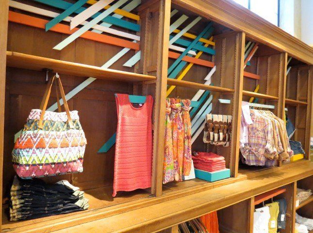 A row of shelves with clothes and bags on them