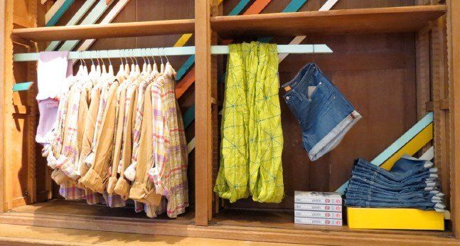 A wooden closet filled with clothes and a yellow scarf