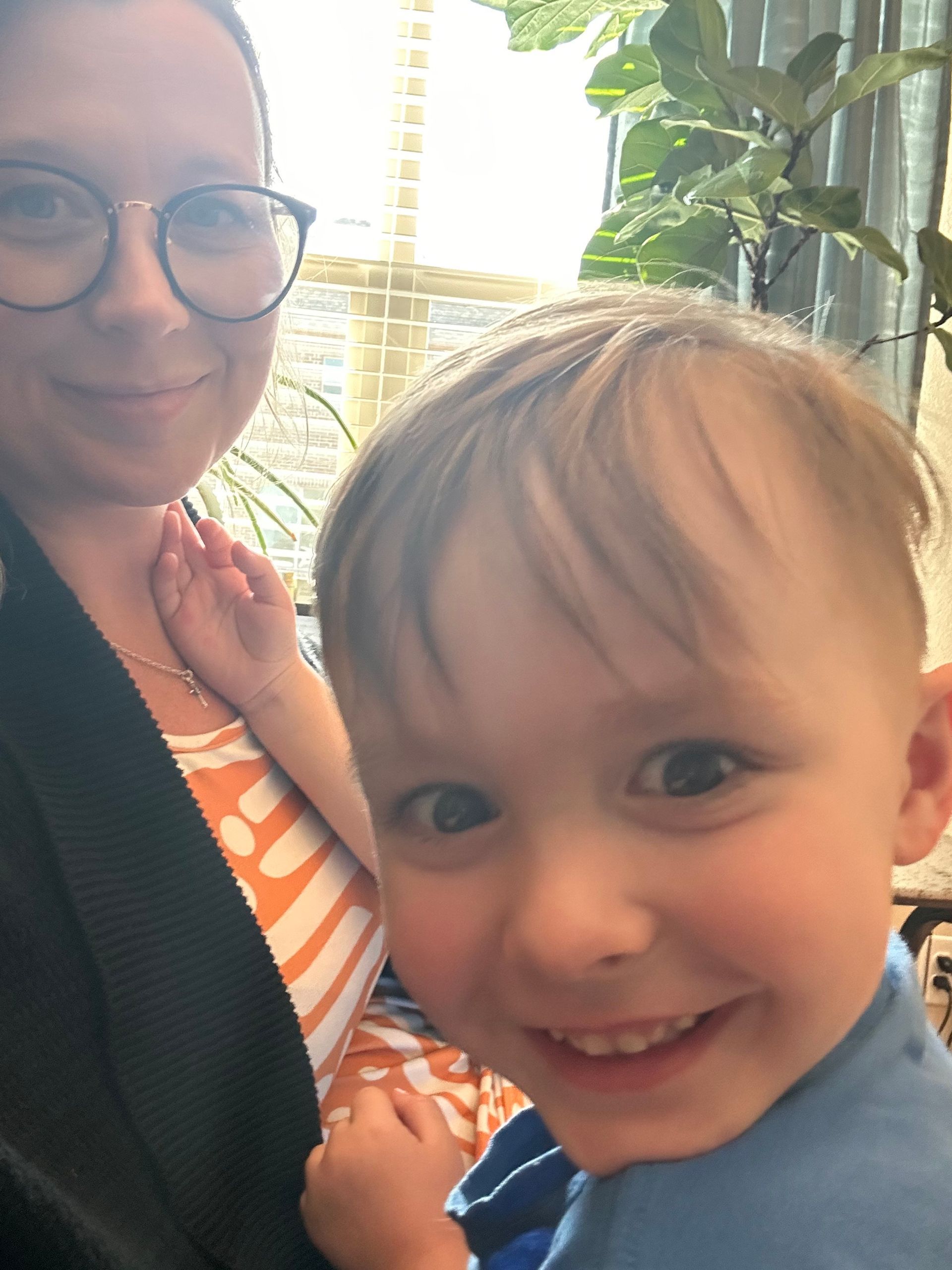 A woman is holding a little boy who is smiling for the camera