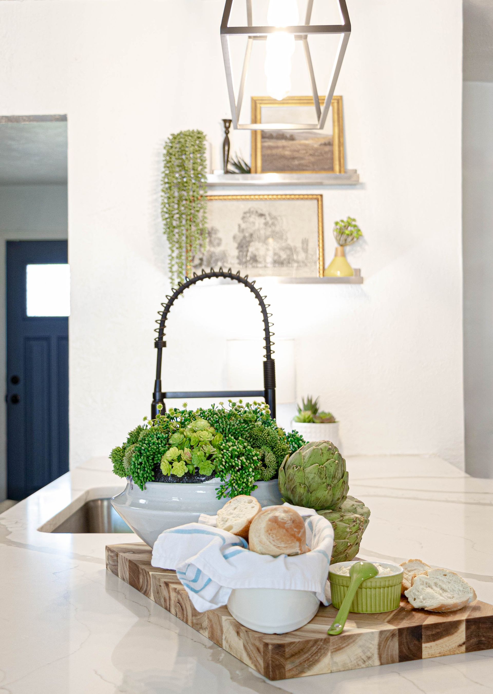 A kitchen with a sink , cutting board , bowls of food and a faucet.