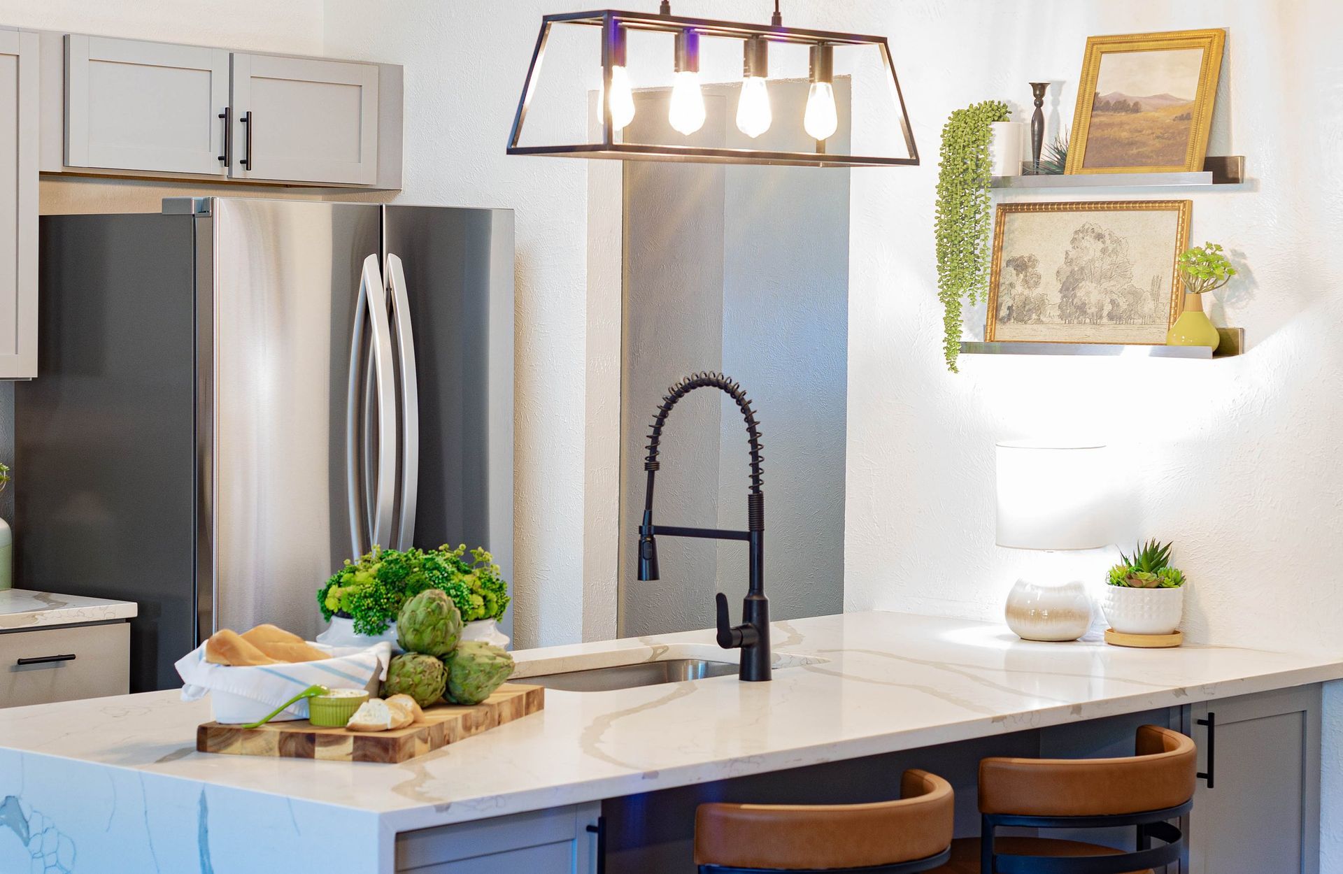 A kitchen with a large island , sink , refrigerator and stainless steel appliances.