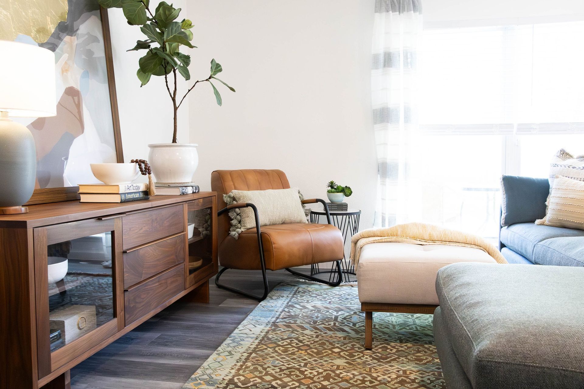 A living room with a couch , chair , ottoman and dresser.