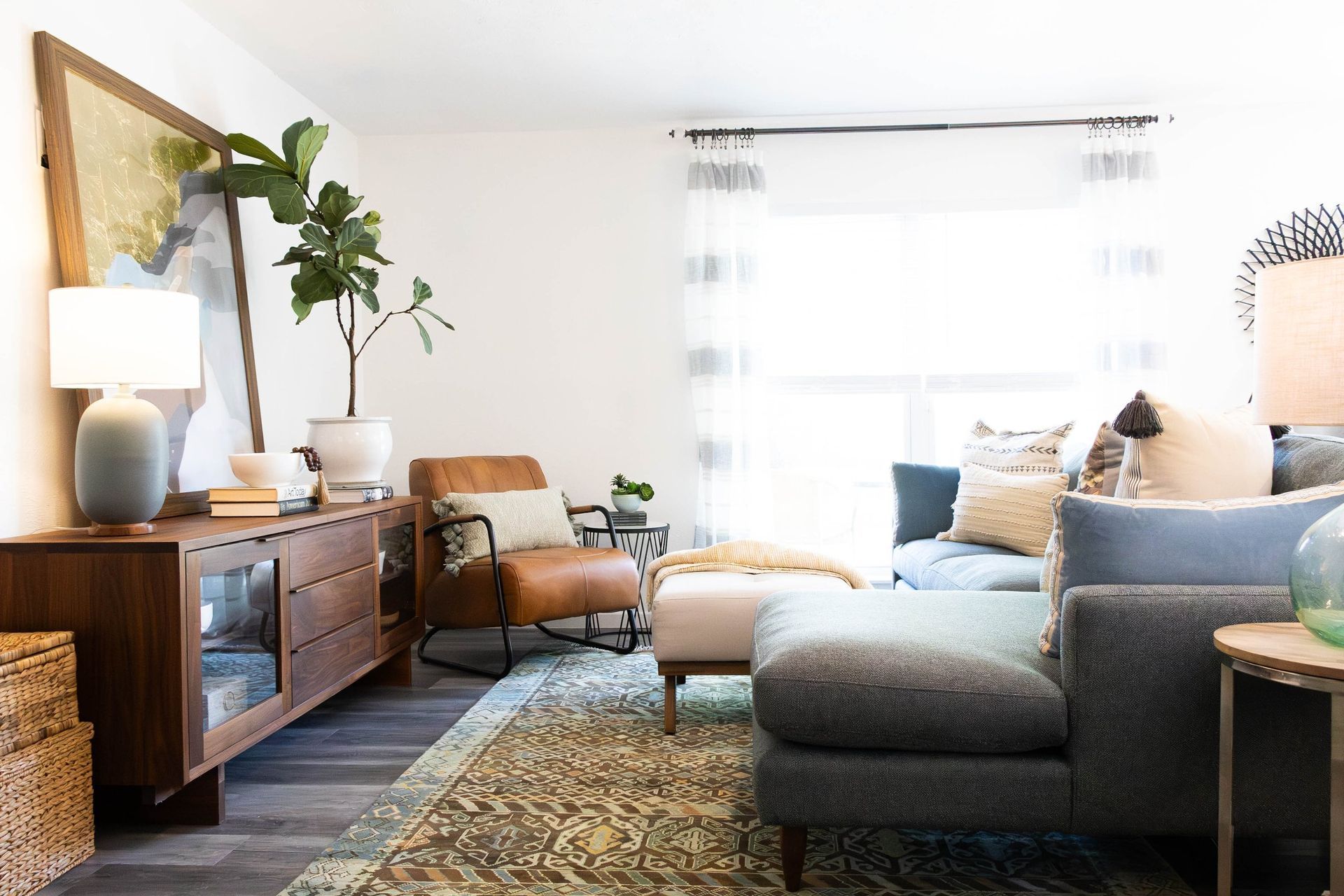 A living room with a couch , chair , ottoman and dresser.