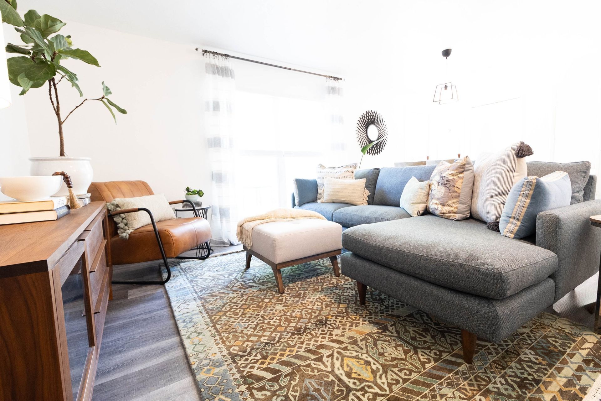 A living room with a couch , chair , ottoman and rug.