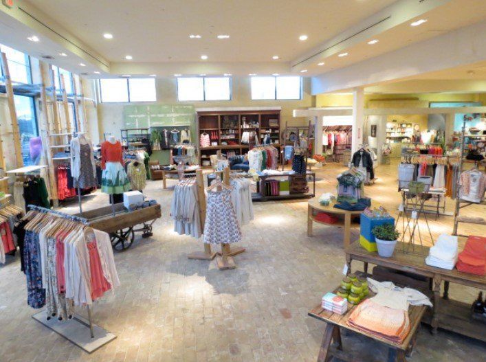 A blurred image of a clothing store with a lot of clothes on display.