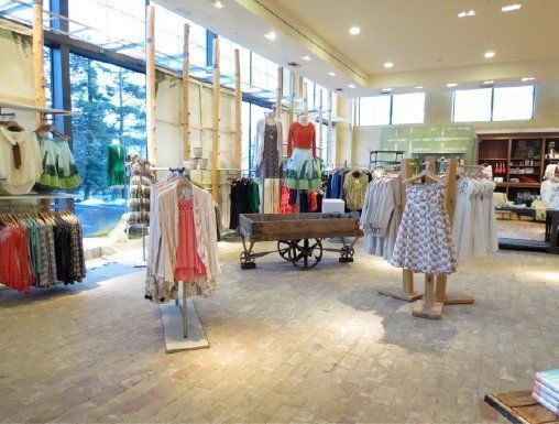 A store filled with clothes and a cart with clothes on it.