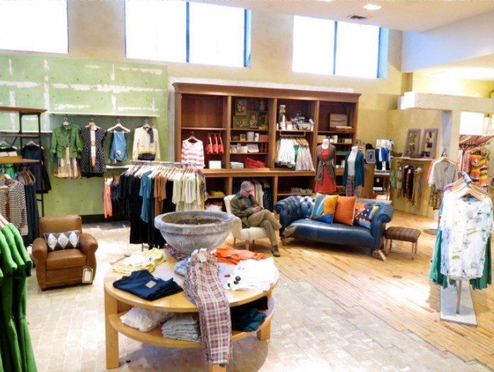 A man sits on a couch in a clothing store