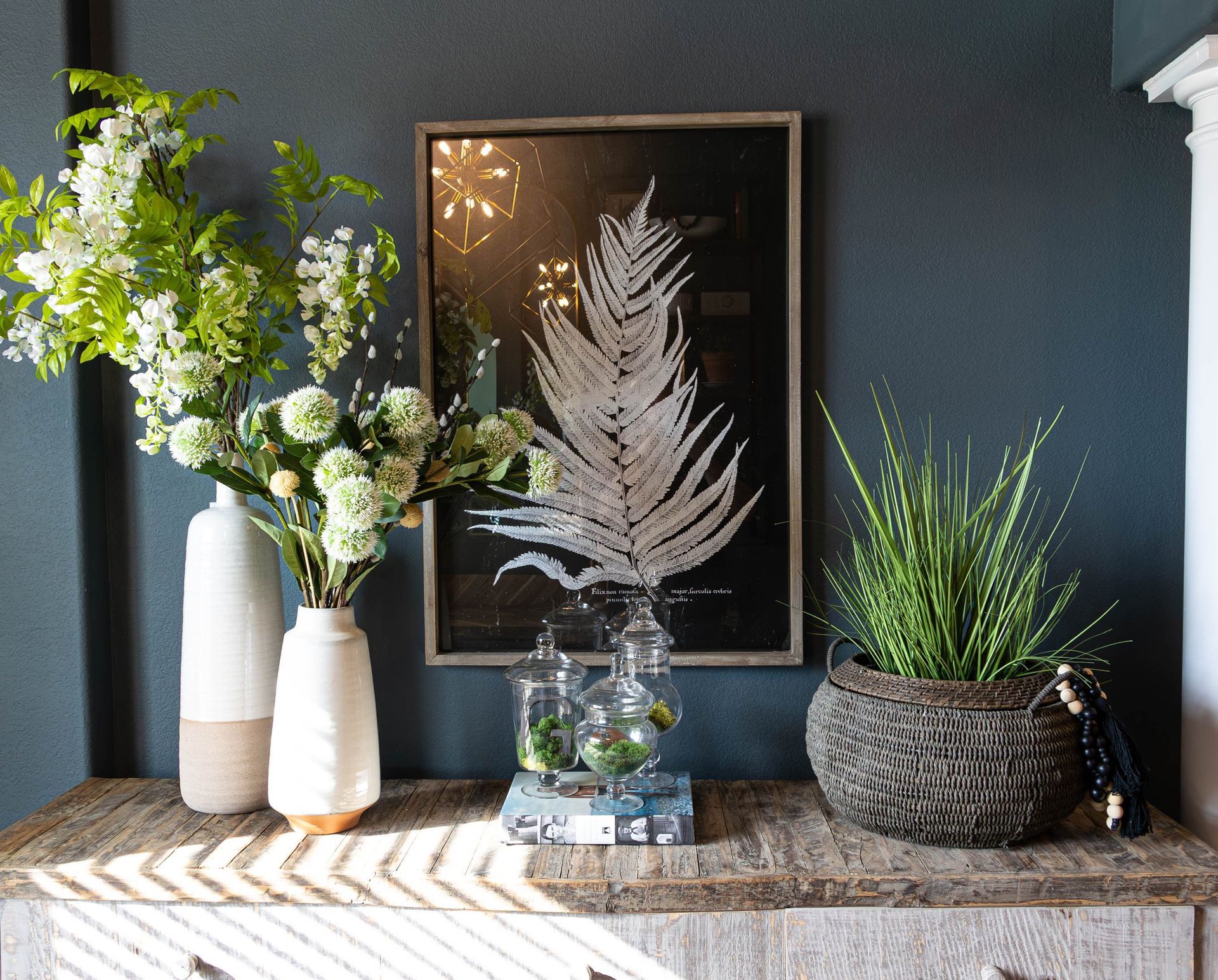 A vase of flowers sits on a table next to a picture of a palm tree