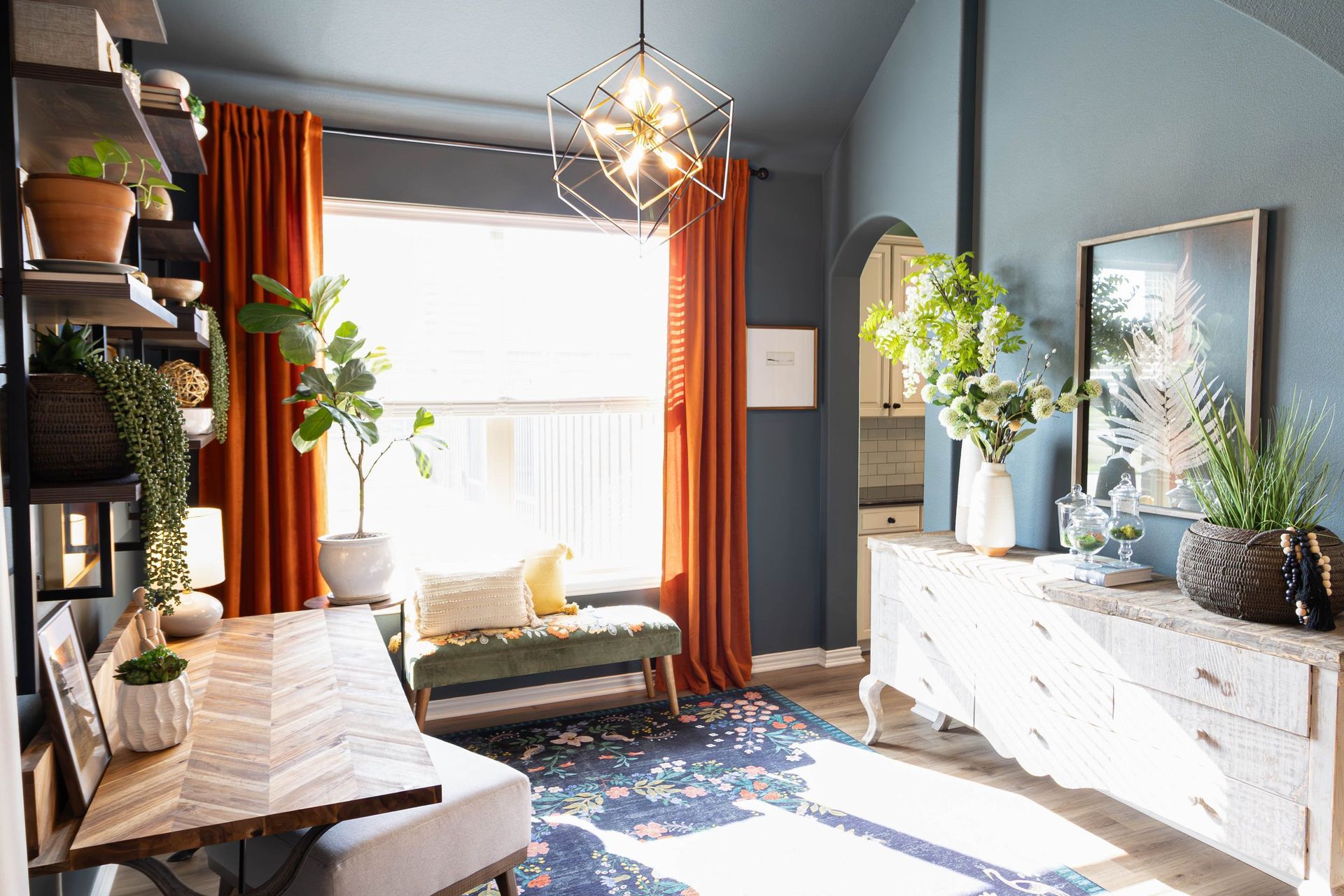 A living room with a table , bench , dresser and window.