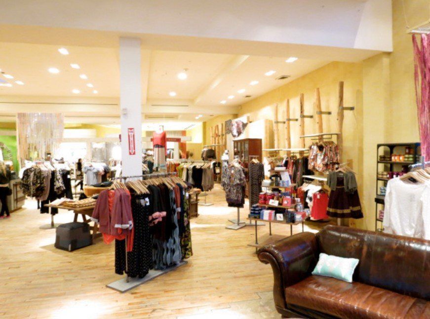 A leather couch is in the middle of a clothing store