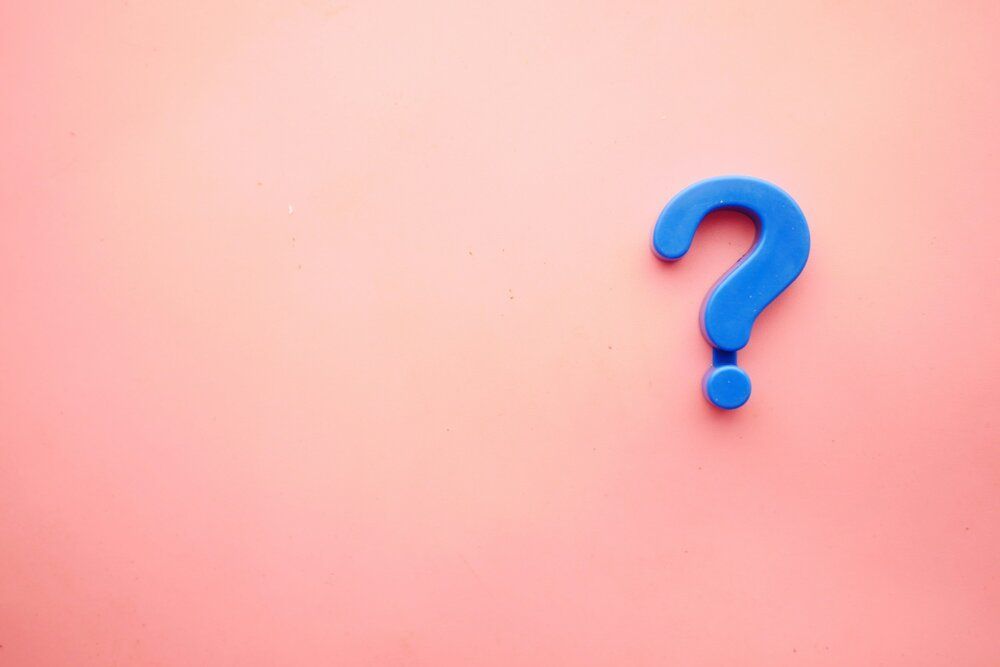 A blue question mark on a pink background.