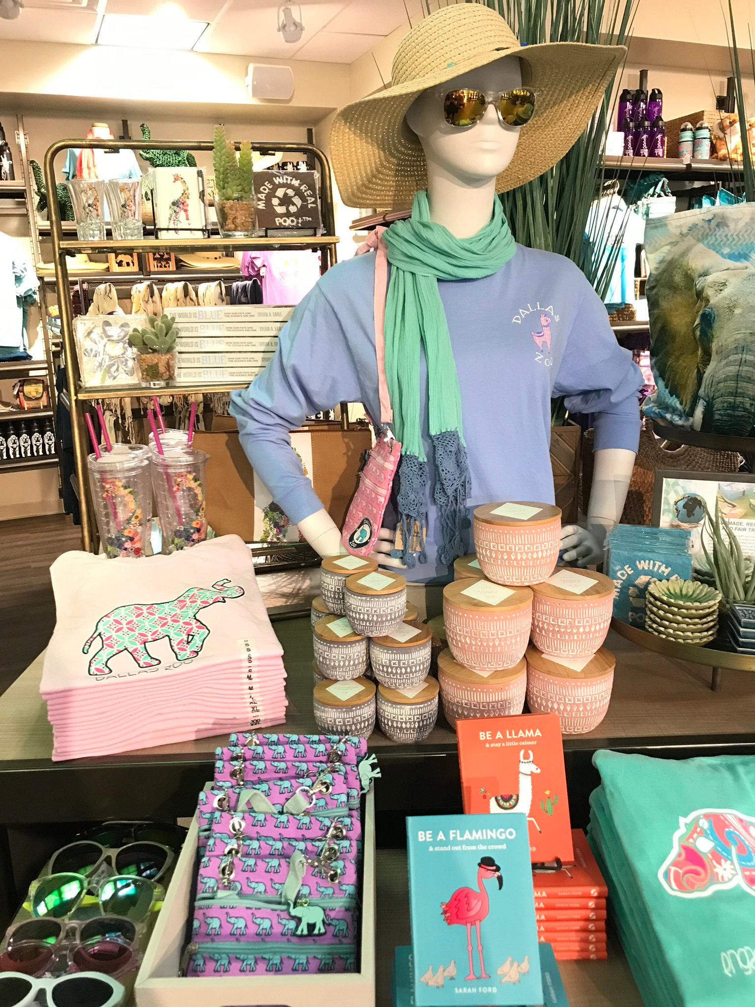 A mannequin wearing a straw hat and sunglasses is standing in a store.