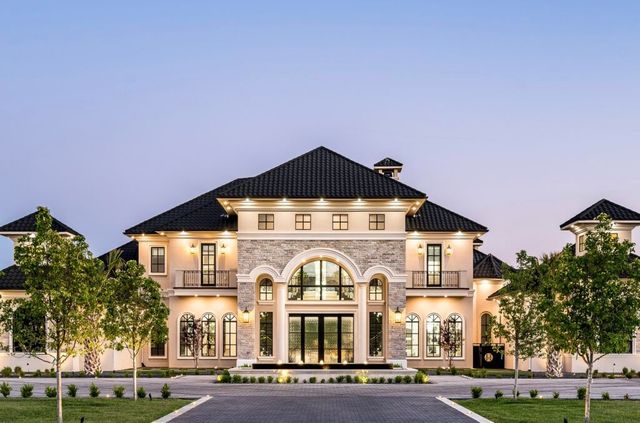 A large house with a black roof is surrounded by trees