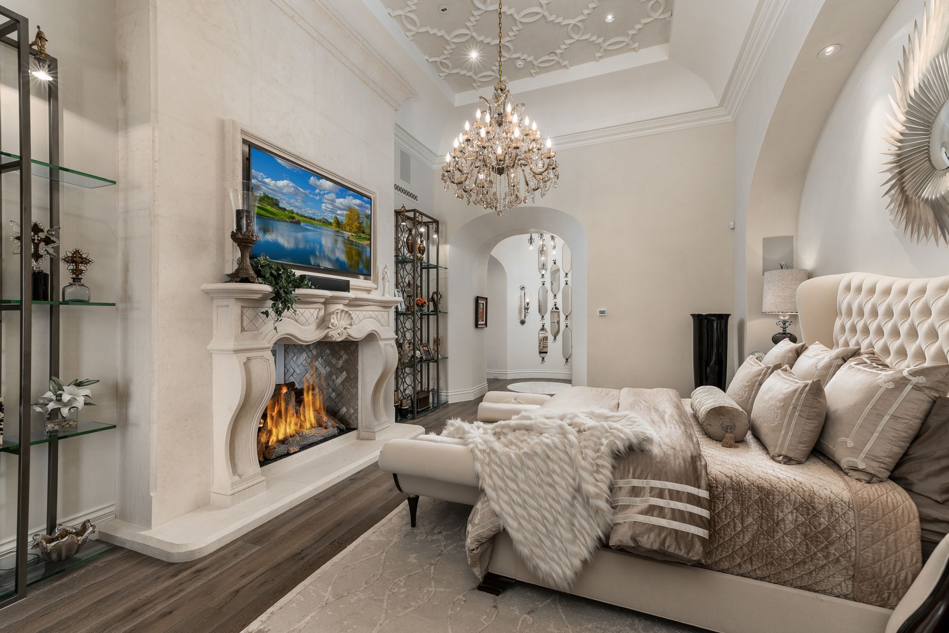 A bedroom with a bed , fireplace , television and chandelier.