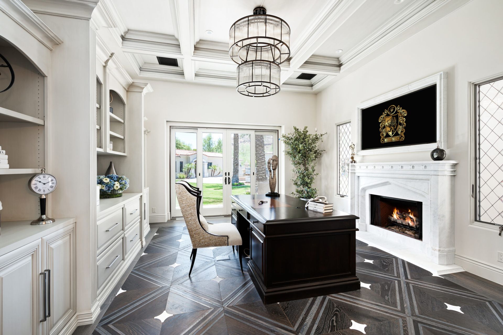 A home office with a desk , chairs , fireplace and television.