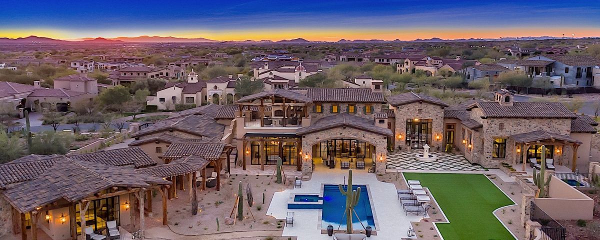 An aerial view of a large house with a pool in the middle of it.